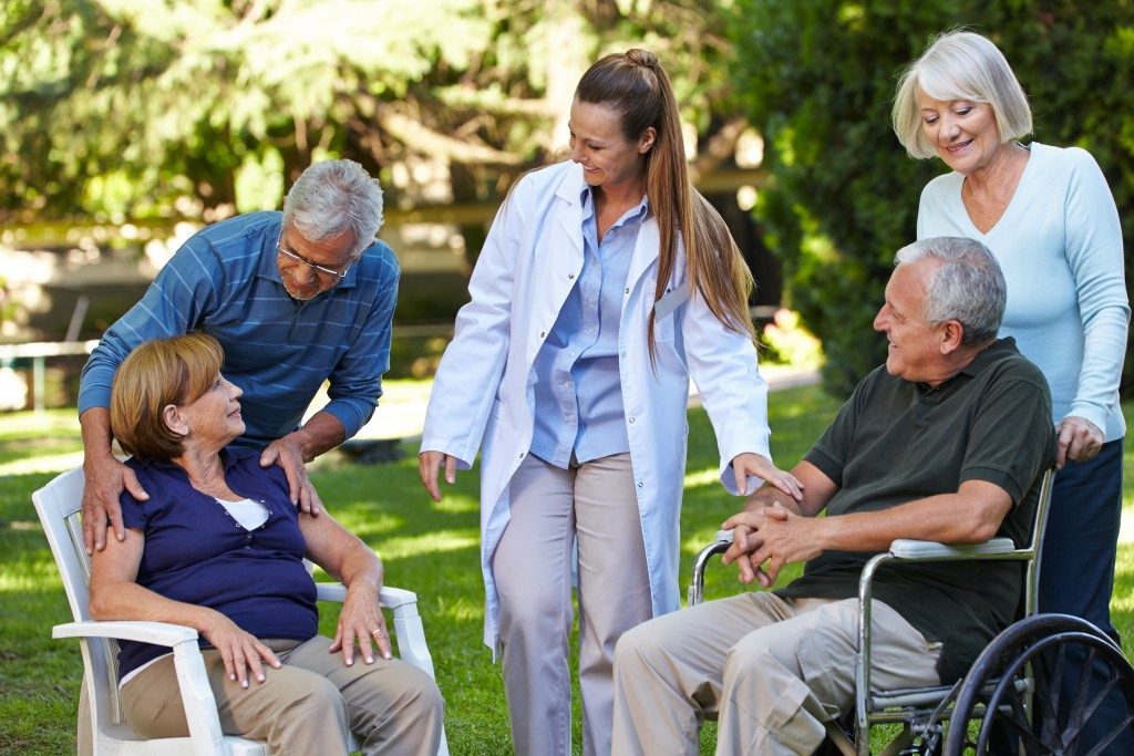 Seniors relaxing in the park with a nurse
