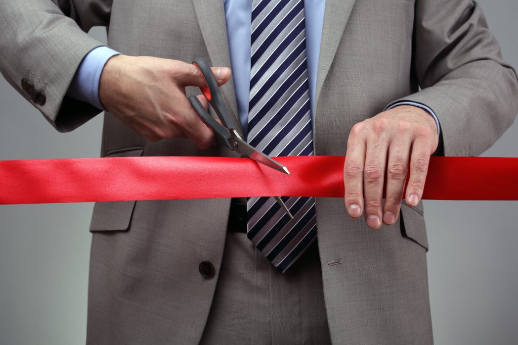 man cutting a red ribbon