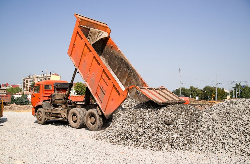 The truck pours the crushed rocks on the road construction