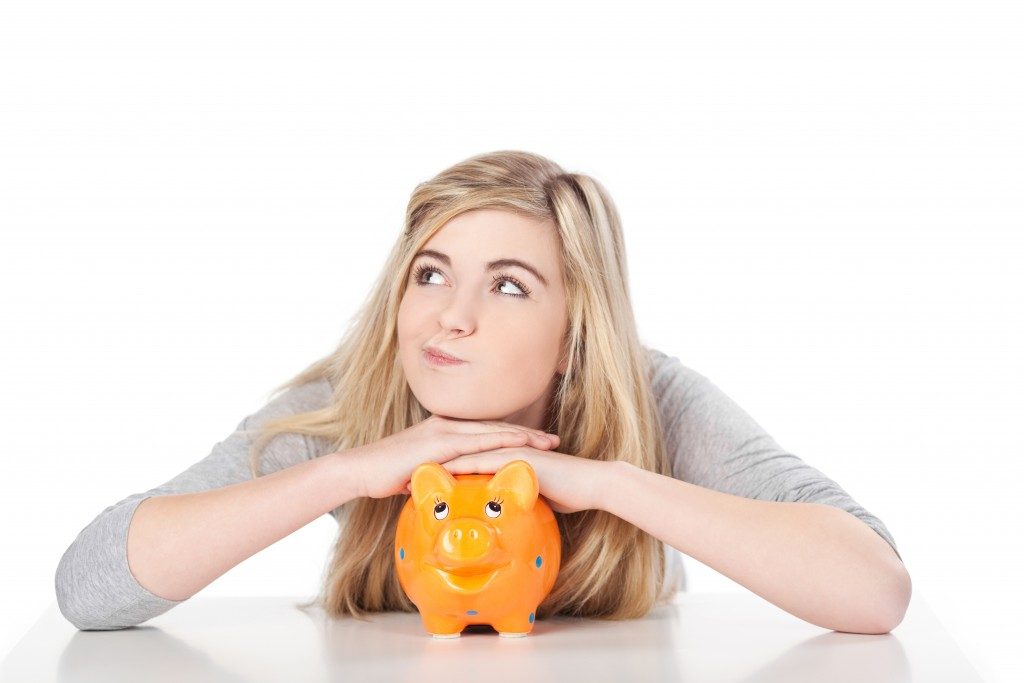 Image of a cute teenage girl posing with piggy bank.