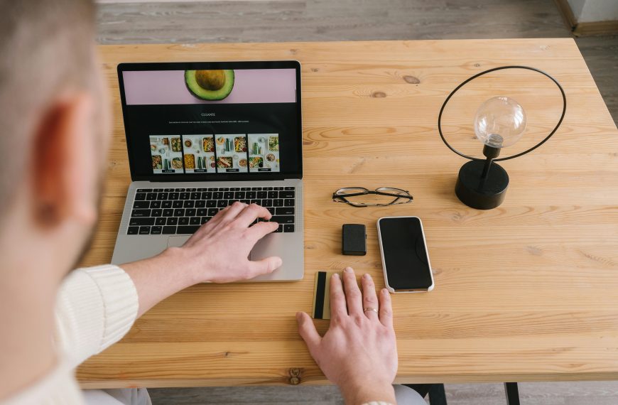 man building a website, with a smartphone and glasses next to him on the desk