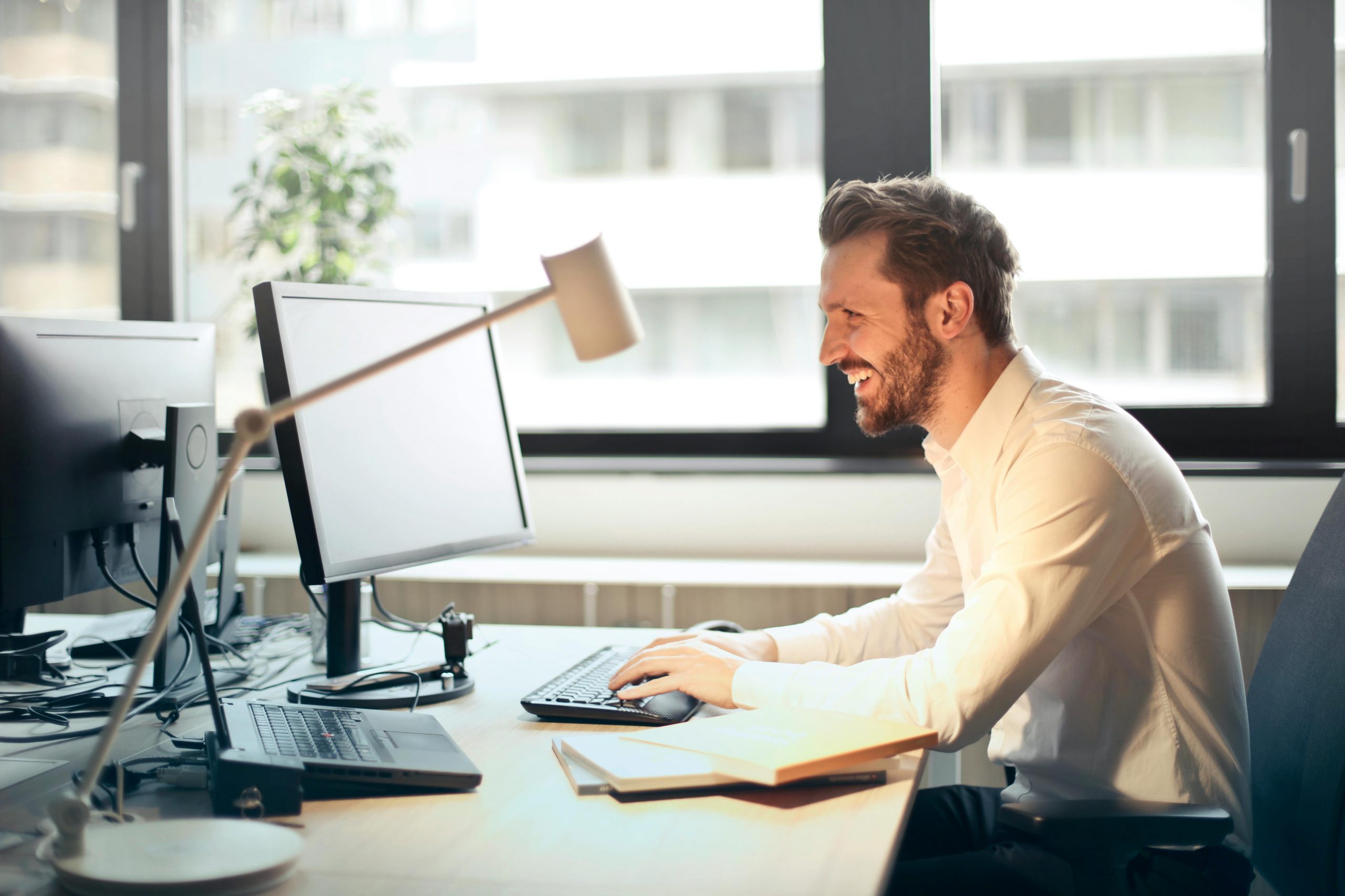smiling man in professional attire working on a desktop computer